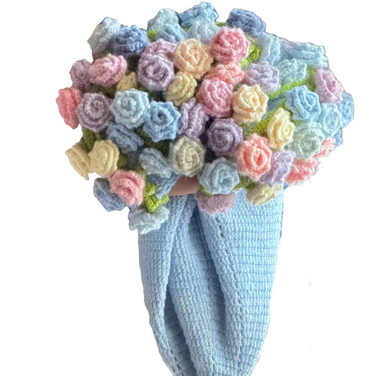 Person holding a colorful bouquet of crocheted flowers against a blurred background