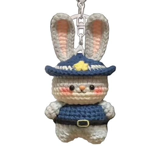 Crocheted rabbit keychain with a blue hat and outfit hanging from a bag.