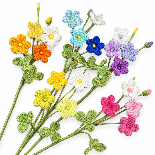 A set of crocheted artificial flowers with green leaves and stems, shown in multiple colors including orange, yellow, blue, purple, pink, and white on a plain white background.