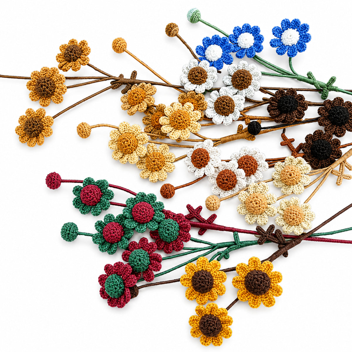 A collection of crocheted floral stems arranged on a white background, featuring sunflowers, daisies, and poppies in yellow, brown, blue, white, green, red, and dark brown yarn.