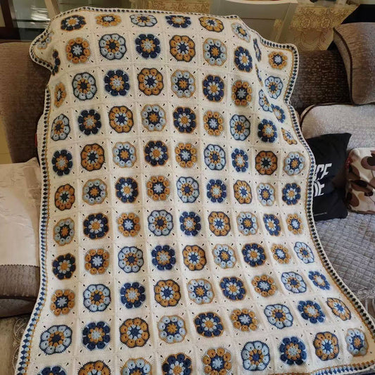Colorful crocheted blanket with a geometric pattern on a couch.