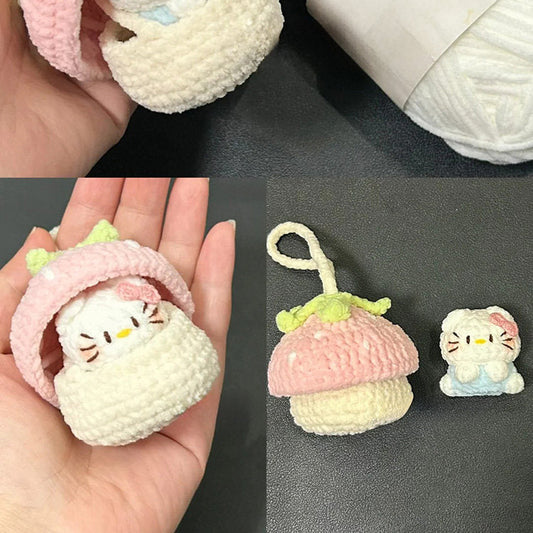 Small crocheted toy resembling a cat in a pink hat next to a ball of white yarn on a dark surface.