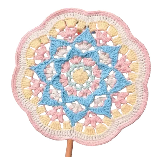 Colorful crocheted mandala on a stand with a blurred outdoor background