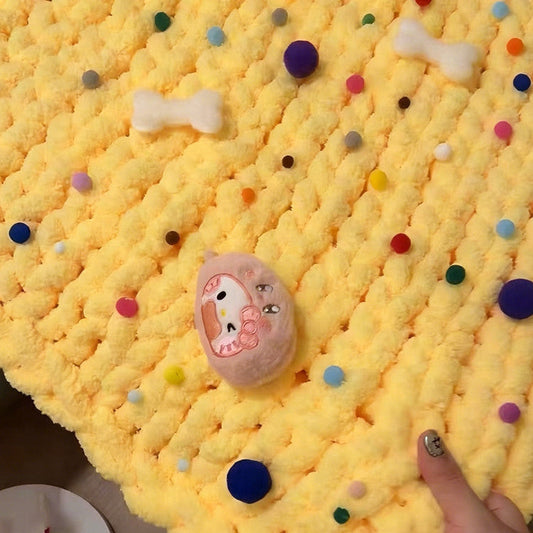 Yellow textured blanket with colorful polka dots held by a hand