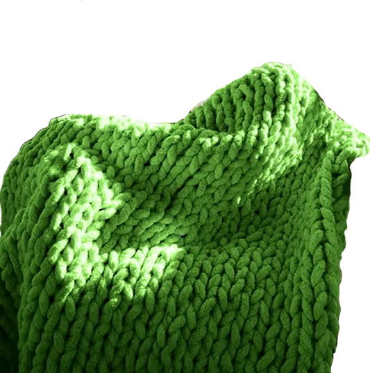 Person sitting on a couch with a green chunky knit blanket draped over them