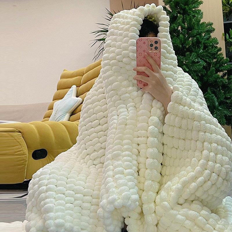 Person wrapped in a large white textured blanket with a blurred indoor background