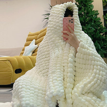 Person wrapped in a large white textured blanket with a blurred indoor background