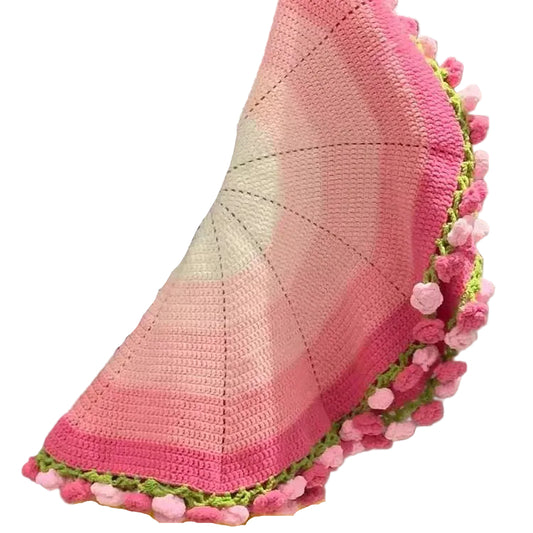 Person holding a crocheted blanket with pink and green border