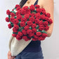 Person holding a large bouquet of red crocheted roses against a white background