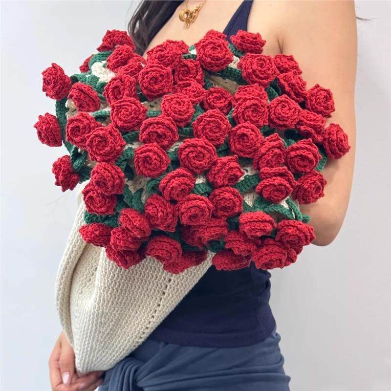 Person holding a large bouquet of red crocheted roses against a white background