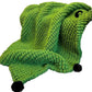 Green textured blanket draped over a chair in a living room setting
