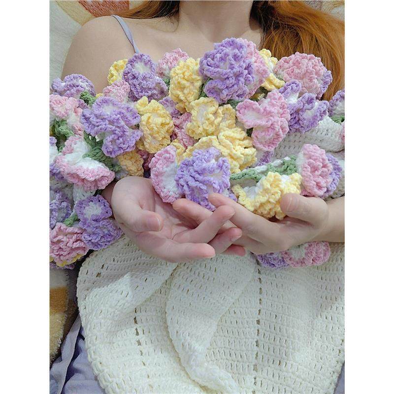 Pastel-colored crocheted flowers held by a person wearing a white lace garment.