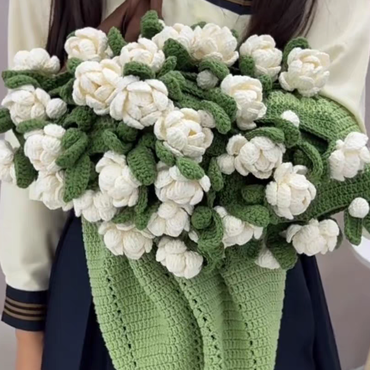 Person holding a large bouquet of white flowers with green leaves