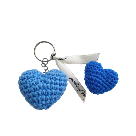 Blue heart-shaped keychain on a white plate with a white cloth background