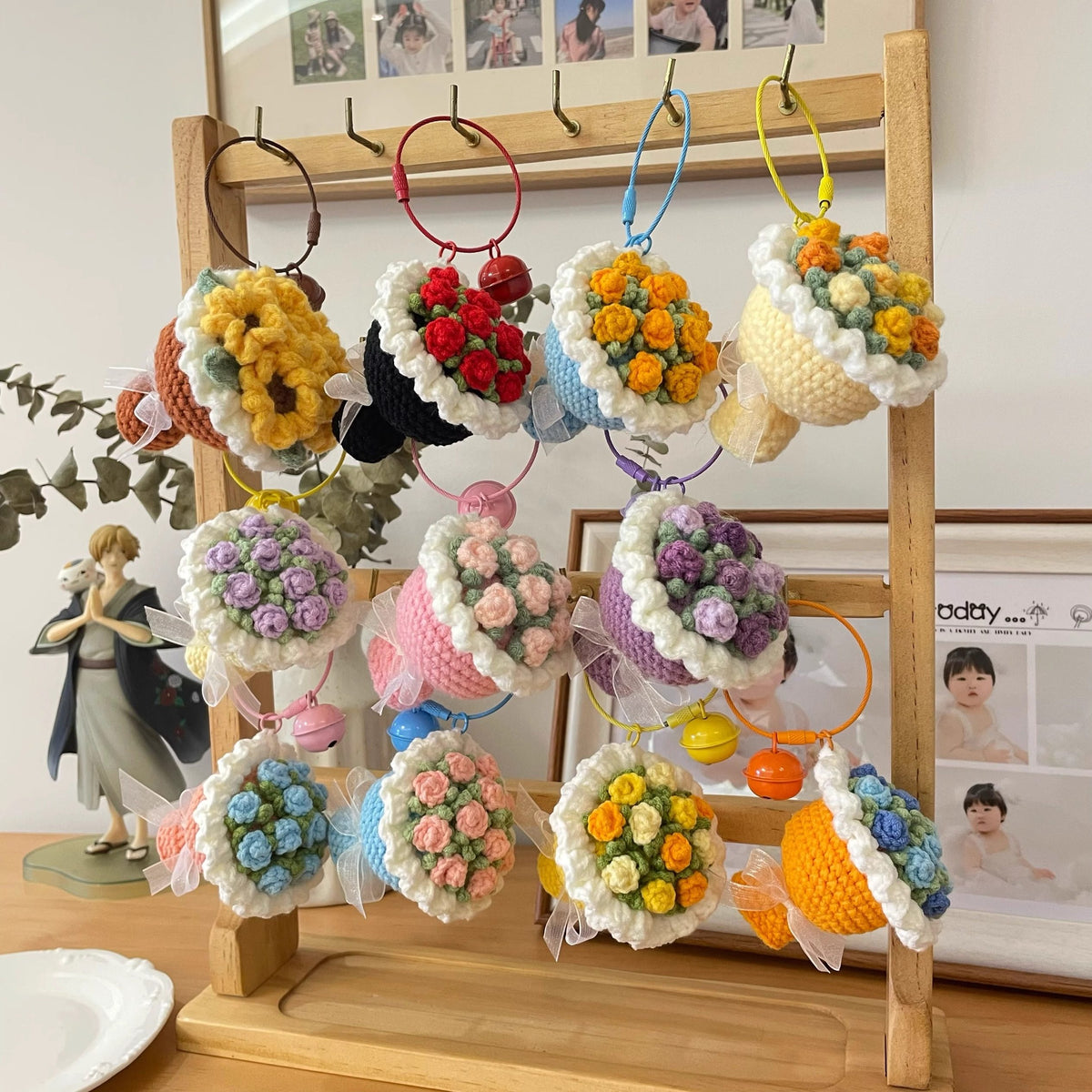 Colorful knitted flower bouquets hanging on a wooden stand with a decorative background.