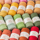 Assorted colorful yarn skeins with labels on a white background
