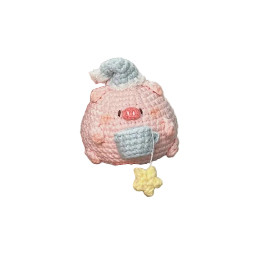 Hand holding a small pink and blue crocheted toy with a gray hat against a plain background