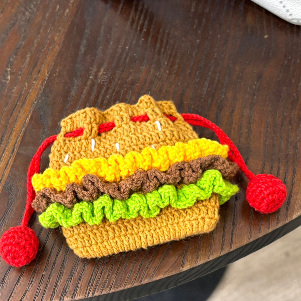 Crocheted hamburger-shaped pouch on a wooden surface