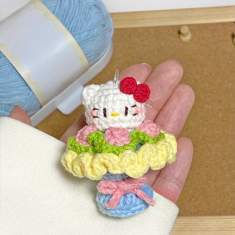 Hand holding a small crocheted character with yarn in the background