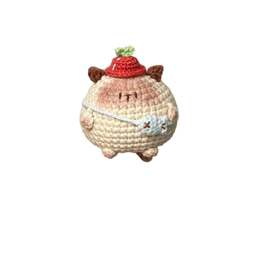 Hand holding a small crocheted character on a needle against a plain background