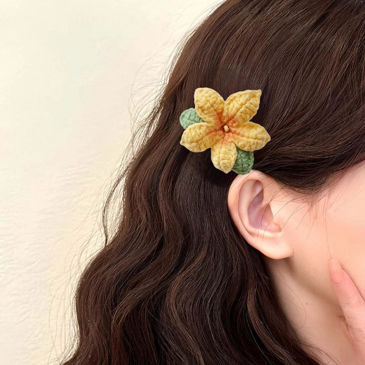 Person wearing a yellow flower hair clip on wavy hair against a neutral background