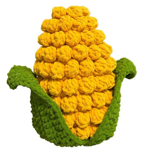 Knitted corn on the cob toy held in front of a neutral background