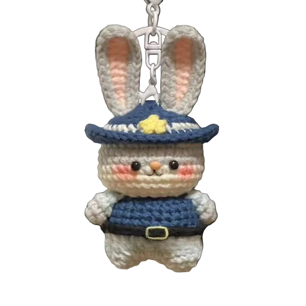 Crocheted rabbit keychain with a blue hat and outfit hanging from a bag.