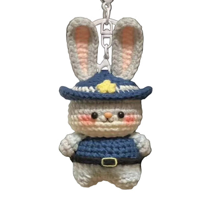 Crocheted rabbit keychain with a blue hat and outfit hanging from a bag.