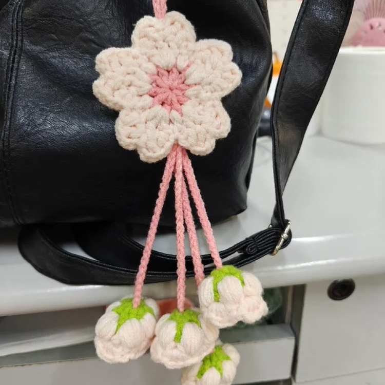 Crocheted flower and berry ornament hanging from a black bag.