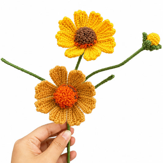 Two crocheted daisy-like flowers with green stems and a small matching bud, held against a white background. One flower is held by a human hand, so this is classified as Lifestyle under the schema rules.