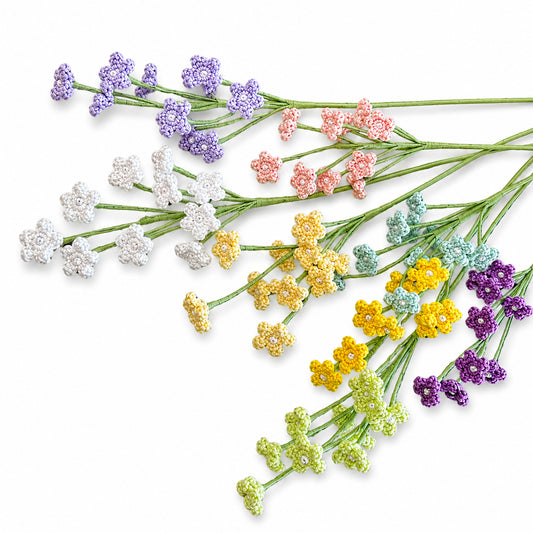 A set of artificial flower stems arranged diagonally on a white background, featuring small clustered blossoms in purple, white, pink, yellow, and light green.