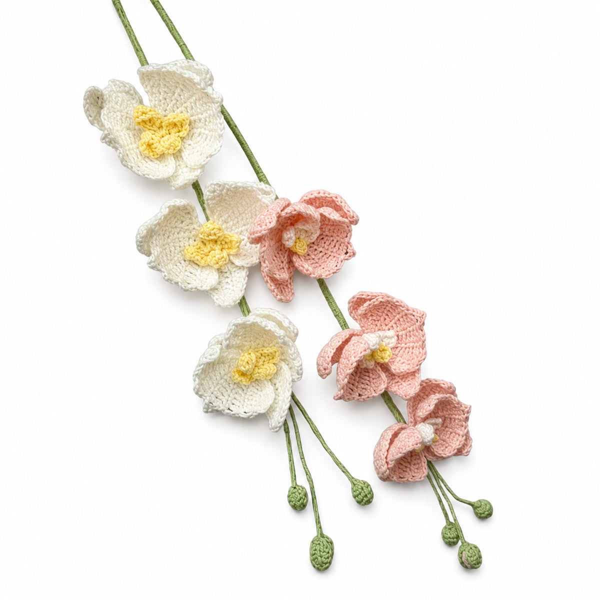Crocheted artificial flower garland featuring white and pink flowers with yellow centers on green stems, photographed on a clean white background.