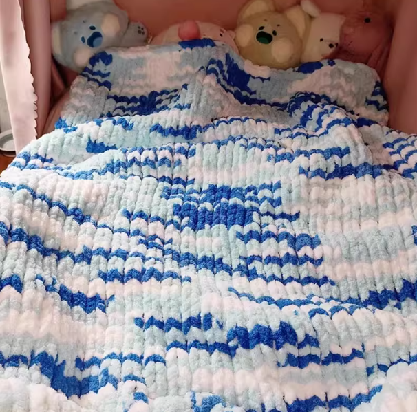 Close-up of a blue and white textured blanket with teddy bears in the background.