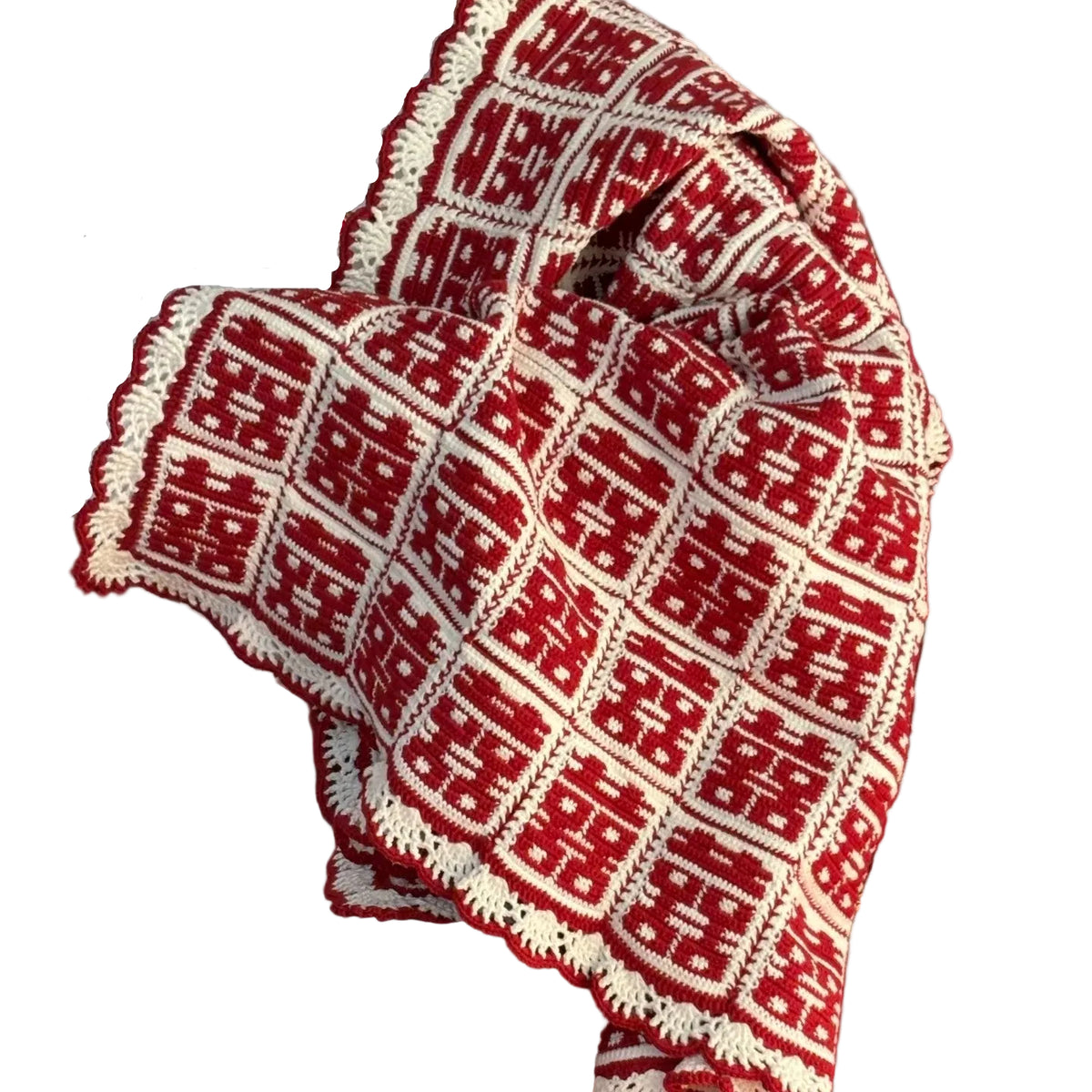 Red and white patterned fabric held by a person in a room with red cushions and a beige sofa.