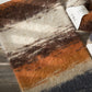 Striped rug with brown, orange, and beige colors on a wooden floor.