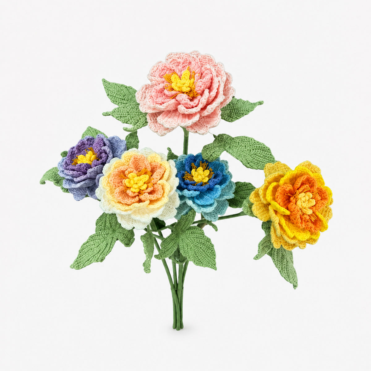 A set of five knitted peony-style flowers in pink, purple, orange, blue, and yellow, arranged with green knitted leaves and stems on a light gray background.
