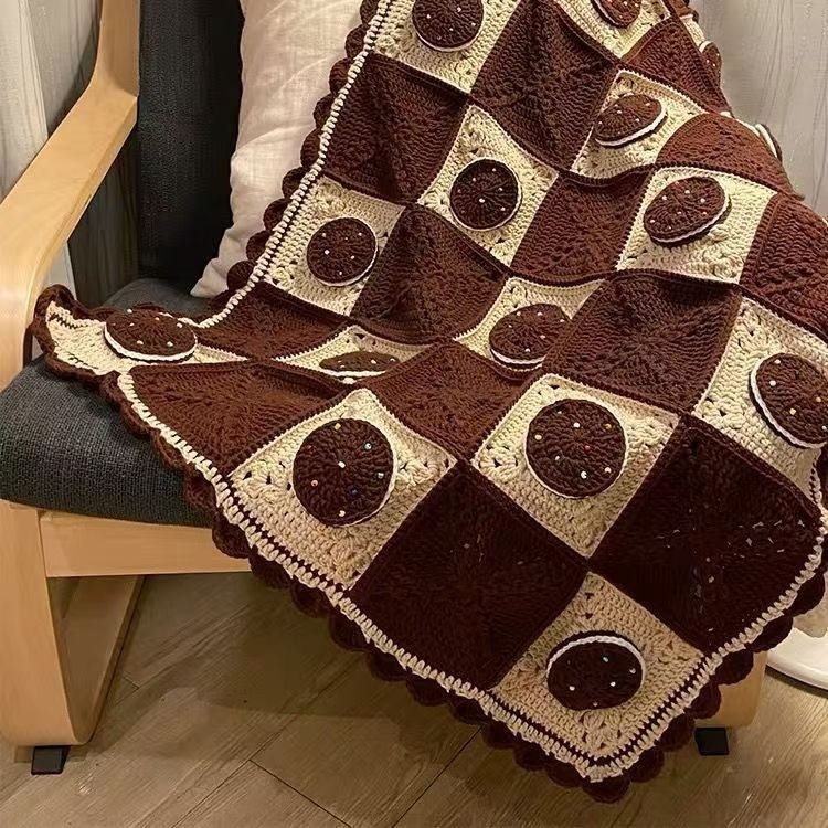 Brown and beige crocheted blanket draped over a chair.