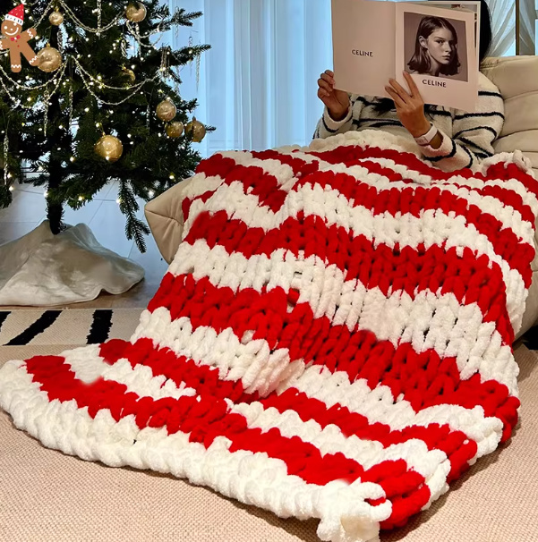Red and white striped blanket draped over a couch with a Christmas tree in the background.