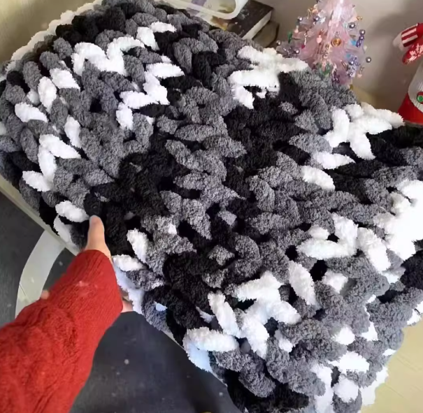 Textured black and white fabric with a hand pointing at it, on a light-colored surface.