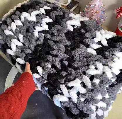 Textured black and white fabric with a hand pointing at it, on a light-colored surface.