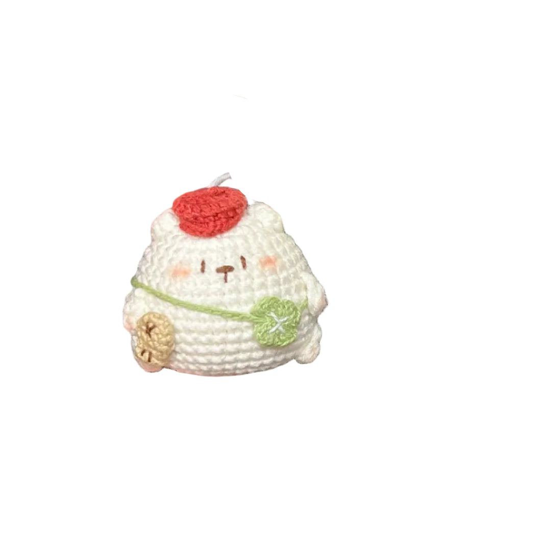 Small crocheted llama toy held by a hand next to a ball of white yarn on a dark surface.