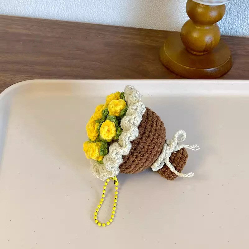 Crocheted flower pot with yellow flowers on a white surface
