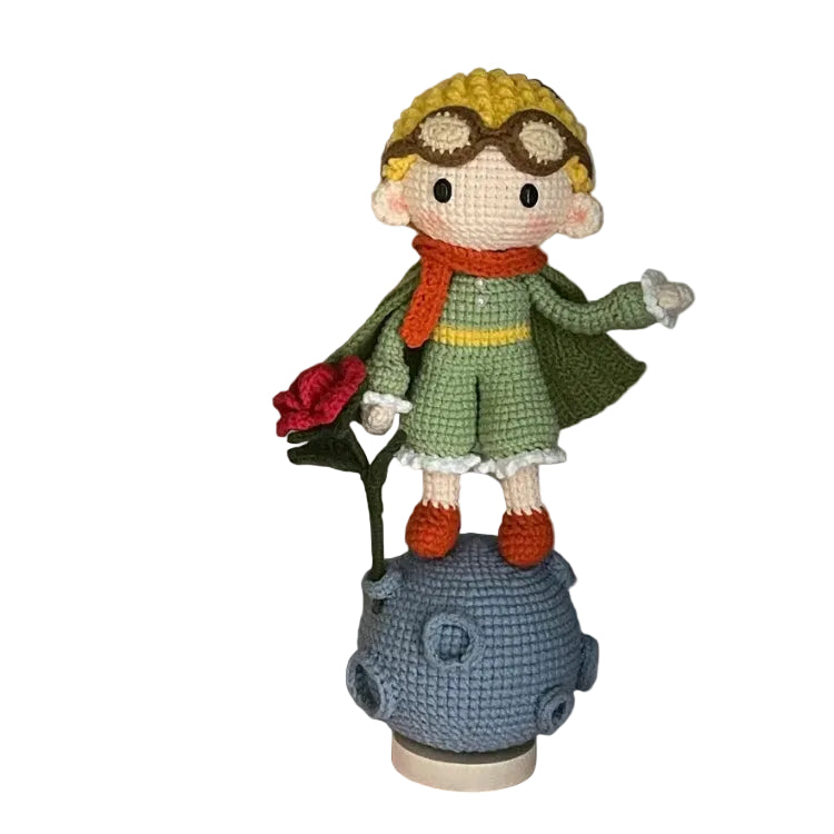 Crocheted doll with a green outfit and yellow hat on a blue stand against a colorful wall.