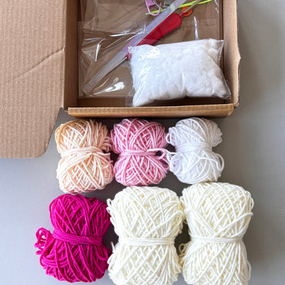 Yarn balls in various colors with a cardboard box containing knitting tools on a light background