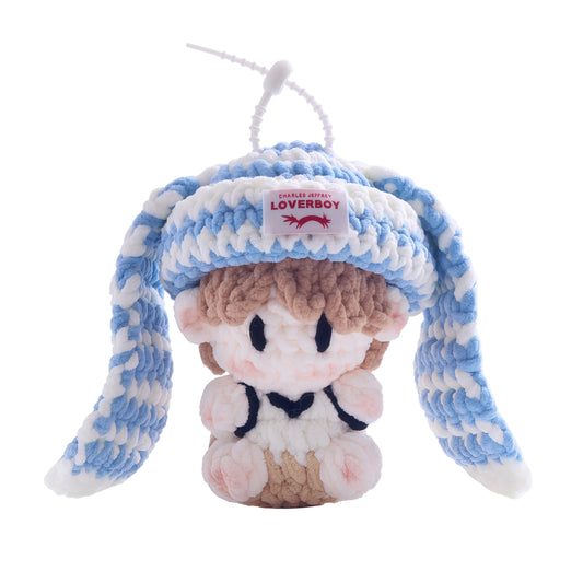 Small plush toy with blue and white striped hat on a white background