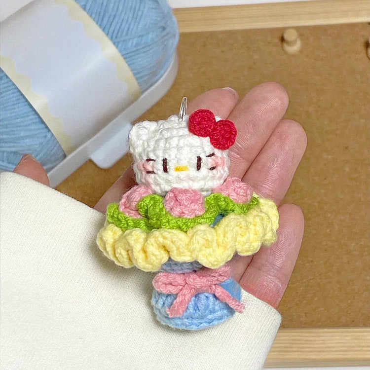 Hand holding a small crocheted character with yarn in the background