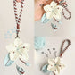 Handmade crochet flower keychain held by a hand with yarn ball and hooks in the background.