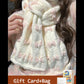 White scarf with pink butterfly patterns worn by a person, with a gift card and bag in the corner.