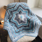 Star-shaped knitted blanket with blue and gray pattern draped over a chair.