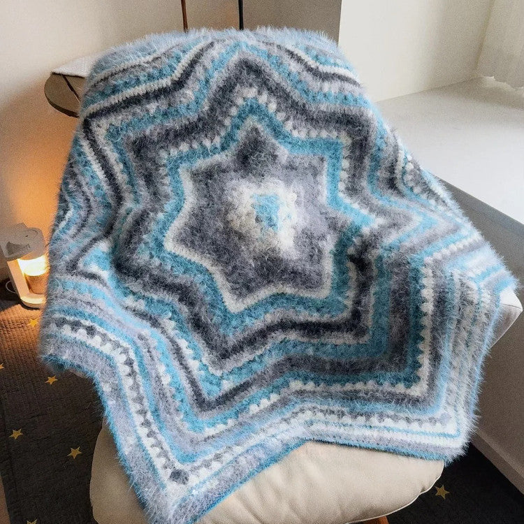 Star-shaped knitted blanket with blue and gray pattern draped over a chair.